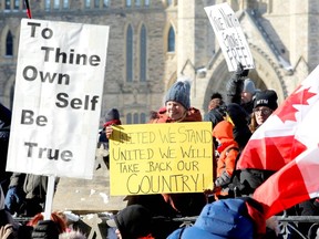 Protestors hold signs in front of Parliament Hill as truckers and supporters take part in a convoy to protest coronavirus disease (COVID-19) vaccine mandates for cross-border truck drivers on Jan. 29. REUTERS