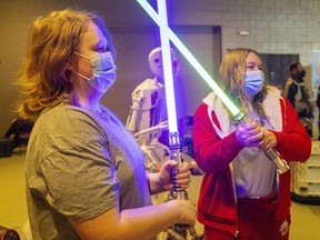 Cousins Aiden Haley of Tillsonburg and Maddie Watson, of London cross lightsabers for their family photos after getting their booster shot at the Agriplex on Feb. 21. Mike Hensen/Postmedia