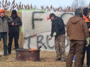 A man lights a campfire where supporters gathered Sunday on land next to a “Freedom Convoy” demonstration that has led to the shutdown of a section of the westbound lanes of Highway 402.
