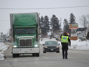 A police officer directs traffic Sunday on London Line at Reece's Corners.  Traffic have been diverted around a section of westbound Highway 402 in Lambton because of a “Freedom Convoy” demonstration.