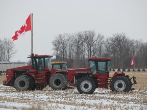 Farm vehicles and a large Canadian flag are shown Sunday in a farm field along Forest Road in Lambton County near a “Freedom Convoy” demonstration that has led to the shutdown of a section of the westbound lanes of Highway 402.