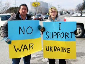 Jeff Plain, an Aamjiwnaang community member, and Kathryn Evans hold signs supporting Ukraine on Saturday, Feb.  26, 2022 in Sarnia, Ont.  Terry Bridge/Sarnia Observer/Postmedia Network