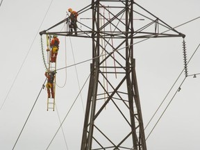Workers from Hydro One work on a transmission tower at Highway 401 and 74 east of London in this file photograph from 2017.  Mike Hensen/Postmedia