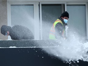 Two people shovel snow off of a flat roof in windy condition in Winnipeg on Wednesday afternoon. Chris Procaylo/Winnipeg Sun