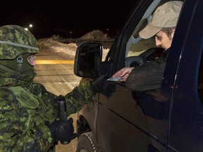 A Wing Auxiliary Security Force member checks a drivers identification during a previous exercise at 22 Wing/CFB North Bay. 
Cpl. Joseph Morin, 22 Wing, CFB North Bay