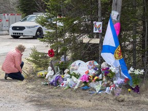 A woman kneels at a memorial to victims of the mass shooting in Portapique, NS, in the spring 2020. The link between hostility toward women and mass killings needs to be addressed, says columnist Robin Baranyai.