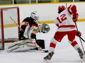 Copper Cliff Reds goaltender Theo Lazure (30) prepares to make a save on Soo Junior Greyhounds forward Ethan Agawa (12) during under-15 AA hockey action at McClelland Arena in Copper Cliff on Saturday, February 26, 2022.