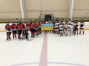 Players from the Copper Cliff Reds U11 hockey team pose for a photo with players from the Nickel City Coyotes U11 squad while holding a Ukrainian flag and with their sticks taped in yellow and blue as a sign of support prior to an exhibition game at McClelland Arena in Copper Cliff, Ontario on Wednesday, March 9, 2022. Each team agreed to make a $100 donation to the Red Cross to support humanitarian efforts in Ukraine, which has been at war since Russia invaded the country on Feb. 24.