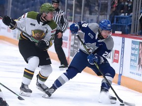Mitchell Russell (27) of the North Bay Battalion battles for the puck with Marc Boudreau (28) of the Sudbury Wolves during OHL action  at Sudbury Community Arena in Sudbury, Ontario on Sunday, March 13, 2022.