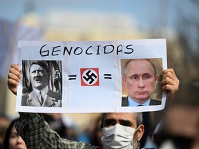 A demonstrator in Madrid holds a sign depicting Russian President Vladimir Putin and Adolf Hitler during a protest against Russia's invasion of Ukraine. GABRIEL BOUYS/AFP via Getty Images