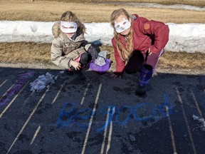 Vigilantes Aurelia and Torrah take kindness into their own hands, letting the community of Airdrie know to be good by writing their message in chalk on the walking paths near Ralph McCall School.