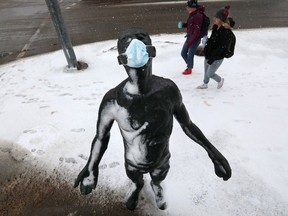 Pedestrians make their way past the sculpture InScope, created by Dan de Nogales, near 87 Avenue and 112 Street, in Edmonton on Sunday, March 20, 2022. A COVID-19 face mask is visible on the sculpture. Photo by DAVID BLOOM / Postmedia.