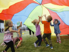Children rush under a colourful parachute.