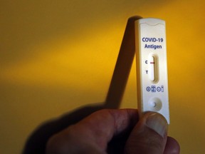 A person holds a COVID-19 rapid antigen testing device showing a negative result.