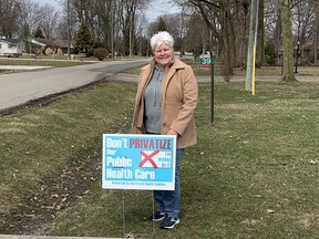 Heather Kavanagh of Chatham is shown with a lawn sign from the Ontario Health Coalition with a message against health care privatization. Area health coalitions are holding a virtual event on the issue on April 7. (Handout/Postmedia Network)