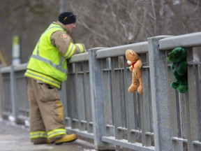 A firefighter scans Whirl Creek from the Wellington Street bridge in Mitchell on Tuesday March 8, 2022. A 10-year-old girl has been missing since falling into the water on Sunday morning. Teddy bears have been affixed along the bridge in support of the girl and her loved ones. (Derek Ruttan/The London Free Press)