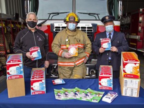John Gignac (left) of the Hawkins-Gignac Foundation for CO Education presents smoke and carbon monoxide alarms to Norfolk County Fire Department firefighters Matt Faulkner (centre) and Jeff Balkwill on Monday in Vittoria.