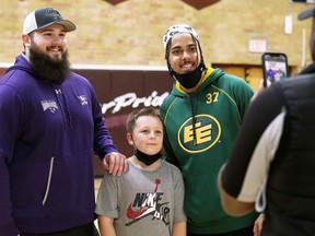 Two-time Vanier Cup champion Austin Fordham-Miller, left, of the Western Mustangs and Edmonton Elks defensive back Josh Woodman pose for a photo with Brady Glassford, 11, of Chatham during a Chatham-Kent Cougars football clinic at John McGregor Secondary School in Chatham, Ont., on Sunday, March 6, 2022. Fordham-Miller and Woodman are Cougars alumni. Quarterbacks coach Jon Dent and receiver Clayton Shreve of the Windsor Lancers also taught at the clinics, which had approximately 65 players. (Mark Malone/Chatham Daily News/Postmedia Network)