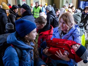 A woman holds a sleeping child as refugees wait for further transportation at the raiway station in Przemysl, Poland on March 17, 2022. - More than three million Ukrainians have fled across the border, mostly women and children, according to the UN. (Photo by Wojtek RADWANSKI / AFP)
