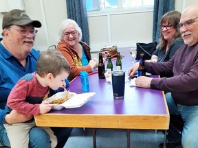 Little Levi Boniakowski seemed to enjoy his spaghetti supper while sitting on his Poppa, Jeff Styler's lap at the Elks Hall on Saturday. Looking on are Jocelyne Bousquet, along with Vickie and Chuck Trahan.
