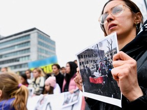 A person holds a picture of a pregnant woman evacuated from a destroyed maternity hospital in Mariupol, Ukraine, during a protest outside the building of the World Court as judges rule on a request from Ukraine to issue an emergency measure to order Russia to cease military activities amid Russia's invasion of Ukraine, in The Hague, Netherlands March 16, 2022. REUTERS/Piroschka Van De Wouw