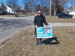 Sarnia-Lambton Health Coalition co-chair June Weiss poses with a lawn sign. The Ontario Health Coalition chapter is trying to make healthcare spending a provincial election issue locally. (Submitted)