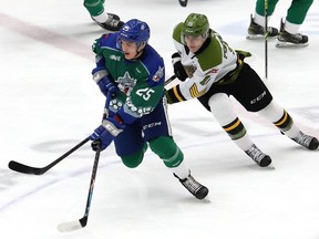 Dominic Jendijk, vlevo, ze Sudbury Wolves, a Michael Podoloch, z North Bay Battalion, závodí s pukem během hnutí OHL v Sudbury Community Arena v Sudbury, Ontario. v pátek 11. března 2022. John Lappa / Sudbury Star / Postmedia Network