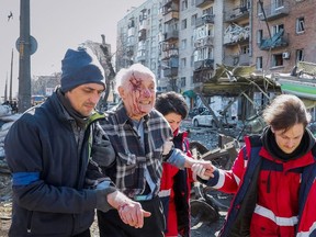 People and medics help a wounded resident of a house destroyed by shelling as Russia's attack on Ukraine continues, in Kyiv, Ukraine March 14, 2022. REUTERS/Gleb Garanich