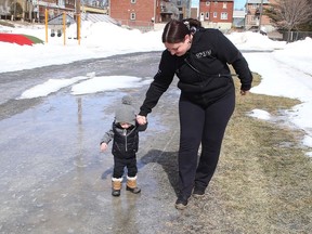 Sarah Land looks on as her son, Issac Evoy, 2, plays in a puddle at Queen's Athletic Field in Sudbury, Ont. on Tuesday March 22, 2022. John Lappa/Sudbury Star/Postmedia Network