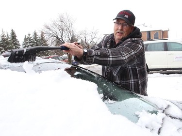 Steven Miller clears snow off his mother's car in Sudbury, Ont. on Thursday March 24, 2022. Environment Canada said Greater Sudbury can expect periods of snow changing to periods of rain or snow near noon on Friday. Temperature will reach 3 C. John Lappa/Sudbury Star/Postmedia Network