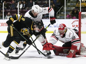 Owen Sound Attack goalie Corbin Votary reaches for the puck as Attack's Madden Steen (5) and Sarnia Sting's Zach Filak (11) battle in front of the net in the first period at Progressive Auto Sales Arena in Sarnia, Ont., on Sunday, March 27, 2022. Mark Malone/Chatham Daily News/Postmedia Network