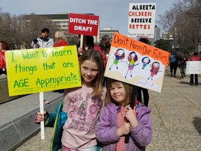 Retired Sherwood Park elementary teacher and grandmother, Jane Hill brought her family to the Legislature on Saturday, April 2 for the Ditch the Draft Rally. Hill's granddaughters, Juliette, 7 and Wren, 5, held signs that read; 'I want to learn things that are age appropriate!' and 'Don't harm our future!' Photo Supplied