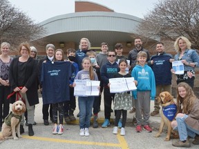Notre Dame Catholic School staff and students and Residential Hospice of Grey Bruce representatives gather at the school where hundreds of school packages were delivered for the annual Hike for Hospice event, which runs throughout May. They were joined by a couple furry friends in Henry, front left, a service dog and the unofficial school dog, and hospice helper Sunny, bottom right, who makes an appearance in the packages.