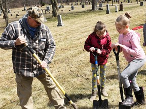 Dresden-area resident Wayne Turner works with Dresden-area central school 3rd graders Ava and Maria to plant a tree at the Dresden cemetery on April 7, 2022. (Tom Morrison/Chatham this week )