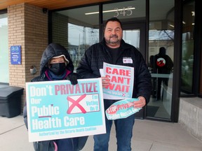 Kaarina Tulisalo, left, and Henri Giroux show off the lawn signs, window signs and stickers that will be part of a campaign opposing private hospitals and private health care in the province, Tuesday.
PJ Wilson/The Nugget