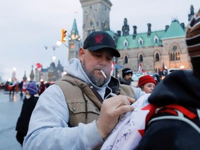Organizer Pat King signs a flag in front of Parliament Hill during February’s occupation. What occupation organizers had in mind was closer to what happened Jan. 6, 2020, in Washington D.C., targeting what they considered to be an illegitimate and despised Trudeau government, writes Tom Mills. REUTERS/Patrick Doyle