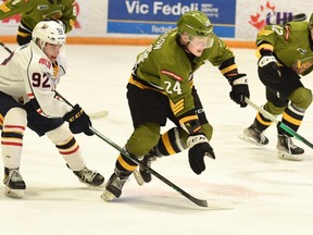 The North Bay Battalion's Ty Nelson, flanked by Nikita Tarasevich, advances the puck against Roenick Jodoin and the visiting Barrie Colts in their Ontario Hockey League game Sunday. The Troops host the Mississauga Steelheads on Thursday night.