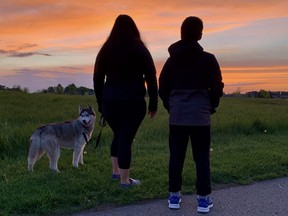 Husky Astro shares a smile while Jessica and Zachary Sooley eye a sweet sunset from west London's Riverbend Park.