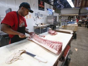 Hashit Haneem, a butcher at SK Quality Meats, cuts up porkloin and loads in into the display case at St. Lawrence Market on Wednesday, April 20, 2022.