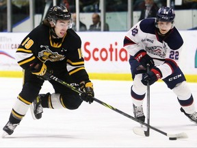 Sarnia Sting's Angus MacDonell, left, battles Saginaw Spirit's Mitchell Smith for the puck in the first period at Progressive Auto Sales Arena in Sarnia, Ont., on Friday, April 15, 2022. Mark Malone/Chatham Daily News/Postmedia Network