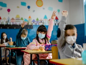 Elementary schoolchildren wearing a protective face masks in the classroom. Education during epidemic.