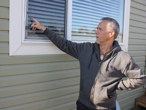 Cam Peneff points to the damage a golf ball did to the window and frame at a neighbour's home. (Ted Murphy)