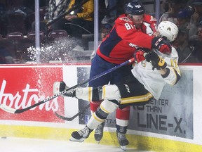 Matthew Maggio, left, of the Windsor Spitfires knocks Alexis Daviault of the Sarnia Sting off his feet on Thursday, April 21, 2022, at the WFCU Centre in Windsor, Ont. (Windsor Star- Dan Janisse)