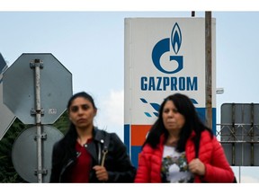 People walk past the logo of energy giant Gazprom at a petrol station in Sofia, Bulgaria on April 27, 2022. Russia's Gazprom said it had stopped all gas supplies to Poland and highly dependent Bulgaria after not receiving payment in rubles from the two EU members.