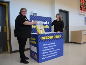 Suzanne Turner (left), general manager at Real Canadian Superstore and assistant manager Nicole Kernche stand with a donation bin with an example of one of the bags of needed items that shoppers can opt in to purchase for the Airdrie Food Bank during the Spring Food Drive. Photo by Riley Cassidy/The Airdrie Echo/Postmedia Network Inc.