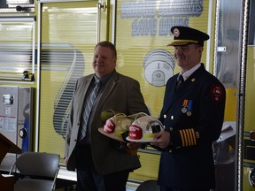 Kevin Weinberger (left) and Mike Pirie stand with their symbolic fire helmets that state their newly-started roles within the community. Photo by Riley Cassidy/The Airdrie Echo/Postmedia Network Inc.