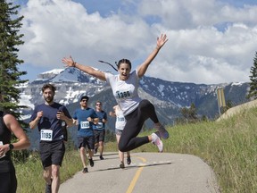 Starting in Banff, participants will flow through a series of incredible natural, wildlife, and historical stages as they pass by the serene Vermilion Lakes and journey along the Bow Valley Parkway. A runner in the Banff Marathon clicks her heels as she runs in the half marathon on Sunday, June 16, 2019. photo by Pam Doyle/pamdoylephoto.com