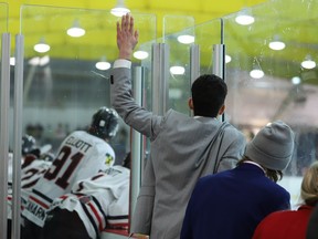 Sidelined Brockville defenceman Anthony Biniaris climbs the glass to get a better look at the action at the other end of the ice during overtime of game seven at the Brockville Memorial Centre early Saturday morning.
Tim Ruhnke/The Recorder and Times