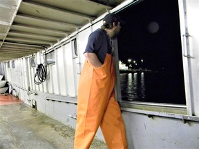 Just after 5:10 a.m. on March 29 aboard the Lady Anna II outbound for Lake Erie. Curtis Mummery stands watch at the port bow hatch. Curtis is watching for "shell" (very thin) ice. Seen through the hatch are the lights of Kingsville harbour. Photo by John Martinello