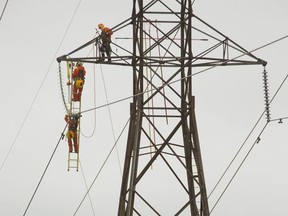 Workers from Hydro One work on a transmission tower in this file photograph from 2017.  Mike Hensen/Postmedia